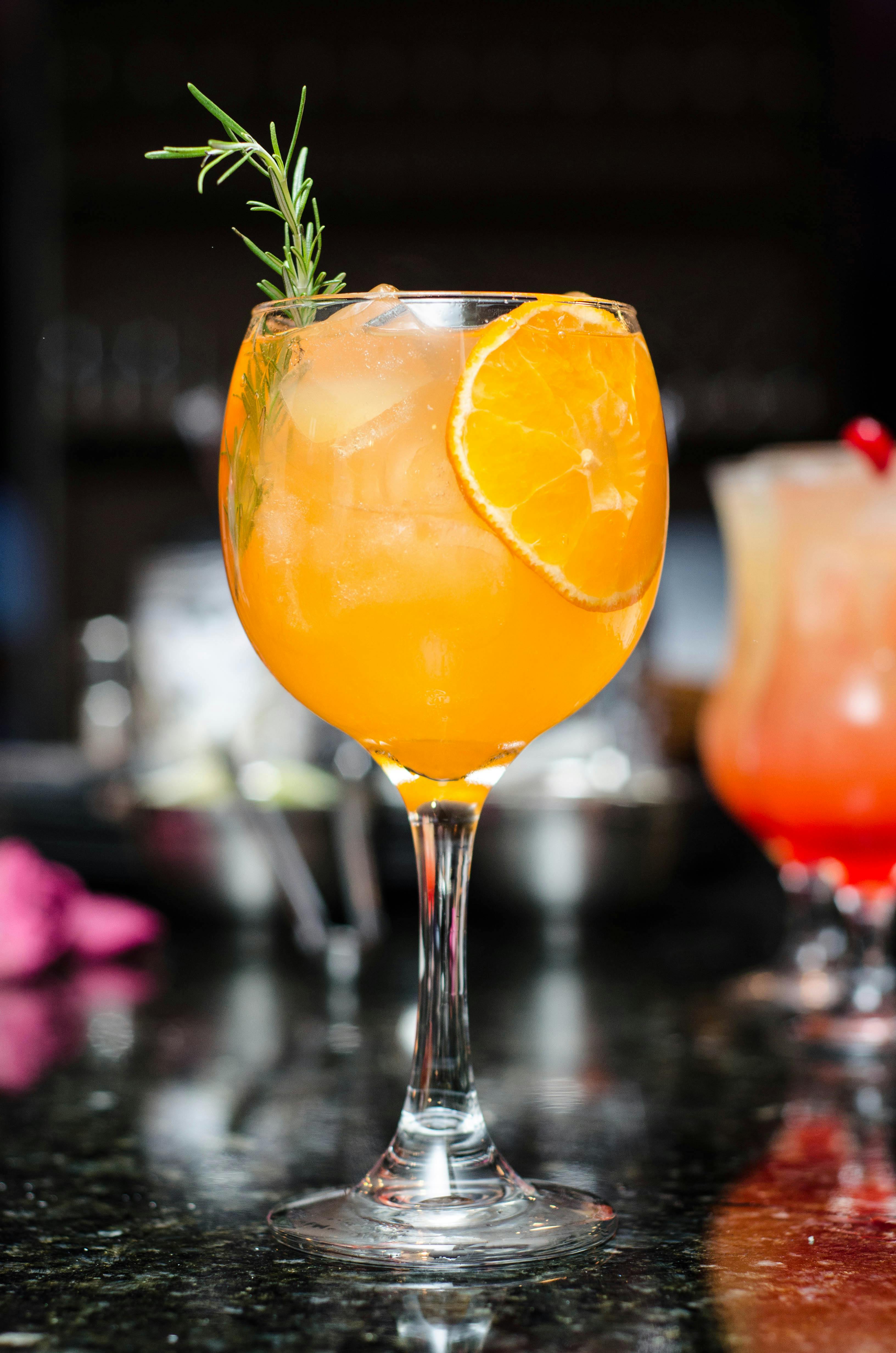 pexels-photo-338713-338713 Refreshing orange cocktail with ice, garnished with rosemary and orange slice. Perfect for summer parties.