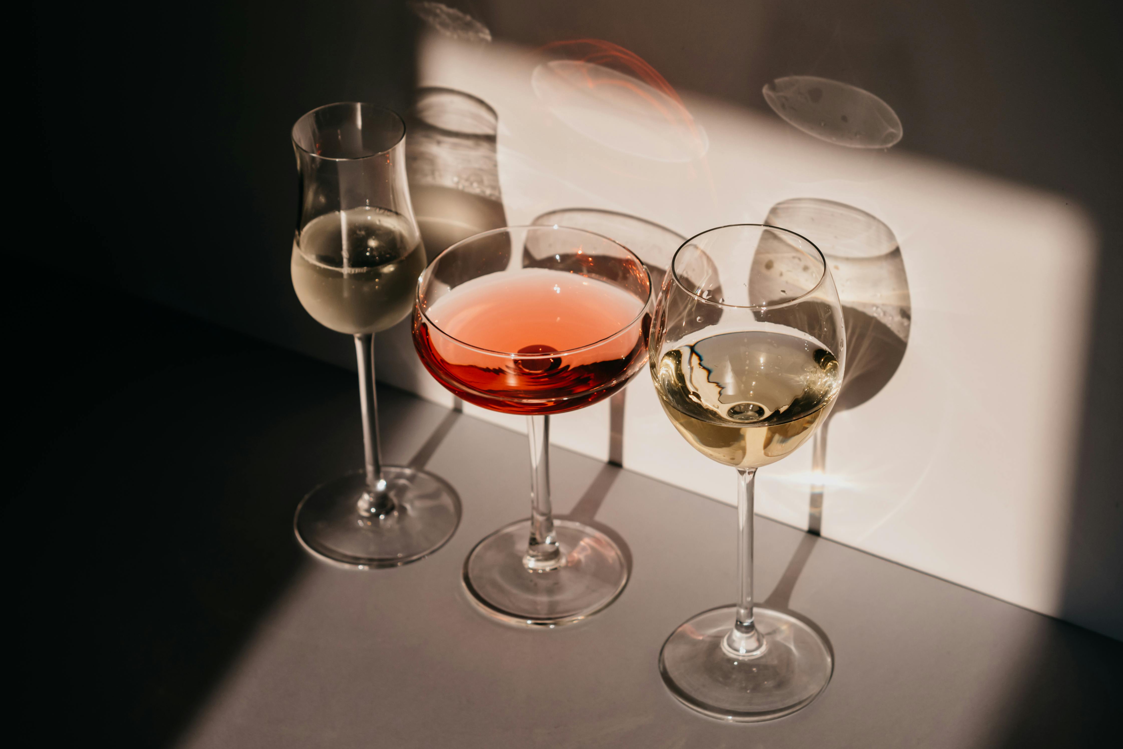 pexels-photo-7270445-7270445 Elegant arrangement of three wine glasses casting distinct shadows in warm light.